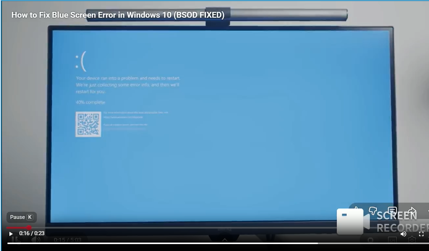 A computer monitor displaying the Windows 10 Blue Screen of Death error message with a sad emoticon, captured from a video tutorial.